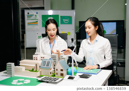 Business professionals presenting sustainable city model with renewable energy, solar panels and wind turbine, green business, ESG, smart city Business professionals presenting sustainable city model with renewable energy, solar panels and wind turbine, green business, ESG, smart city 138546839