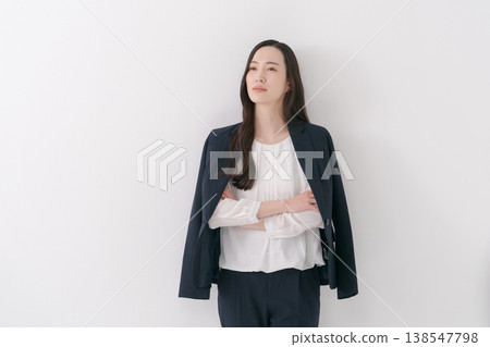 A woman in a suit with her jacket draped over her shoulders. A woman in a suit with her jacket draped over her shoulders. 138547798