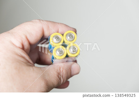 In a hand, close-up: four AAA batteries. 138549325