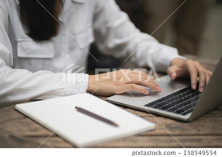 Person Working on Laptop with Notebook and Pen Outdoors in a Natural Setting, Writing Ideas and Taking Notes for Projects and Tasks Person Working on Laptop with Notebook and Pen Outdoors in a Natural Setting, Writing Ideas and Taking Notes for Projects and Tasks 138549554