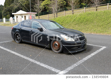 Abandoned car found in park parking lot: No license plates, decaying vehicle, and environmental issues. 138549804
