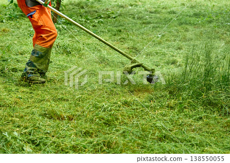 Park summer work.Grass cutting with handle lawn mower Park summer work.Grass cutting with handle lawn mower 138550055