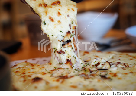 lose-up of Cheesy Pizza Slice Being Pulled with Long Cheese Strings lose-up of Cheesy Pizza Slice Being Pulled with Long Cheese Strings 138550088