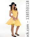 Young woman in summer yellow dress and wide-brim hat posing on white background, summer fashion concept 138550118