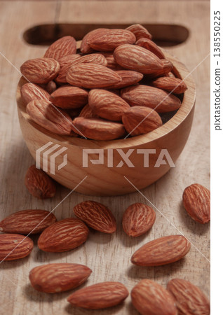 Almonds placed in a wooden cup and on a natural wood plate, highlighting simple organic textures. Almonds placed in a wooden cup and on a natural wood plate, highlighting simple organic textures. 138550225