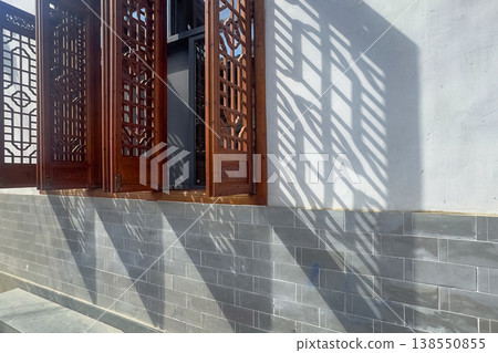 Traditional wooden window casts sharp shadows on gray brick wall Traditional wooden window casts sharp shadows on gray brick wall 138550855