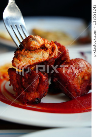 Authentic Indian Chicken Tikka served with spicy red sauce on a white plate. 138551242