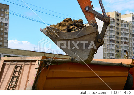 Loading road debris with an excavator into dump truck Loading road debris with an excavator into dump truck 138551490