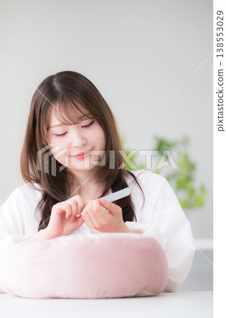 A woman doing self-nail care at home; a beauty lifestyle image of a woman polishing her nails with a nail file. 138553029
