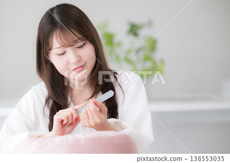 女性在家中進行指甲護理;一張展現女性用指甲銼修整指甲的美麗生活照。 女性在家中進行指甲護理;一張展現女性用指甲銼修整指甲的美麗生活照。 138553035