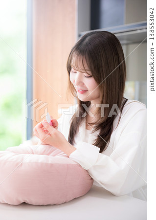 女性在家中進行指甲護理;一張展現女性用指甲銼修整指甲的美麗生活照。 女性在家中進行指甲護理;一張展現女性用指甲銼修整指甲的美麗生活照。 138553042