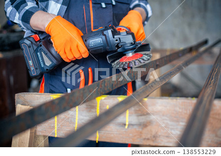 A man cleans metal using an angle grinder. Many sparks 138553229