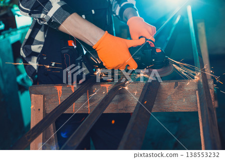 A man cuts metal using an angle grinder. Many sparks 138553232