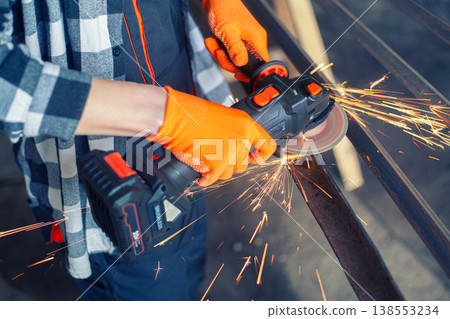 A man cuts metal using an angle grinder. Many sparks 138553234