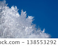 shot of ice crystals. Winter pattern with white snowflakes on the background of the blue sky 138553292