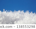 shot of ice crystals. Winter pattern with white snowflakes on the background of the blue sky 138553298