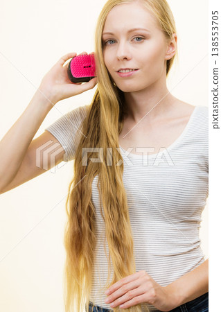 Blonde girl brushing her long hair 138553705