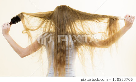 Blonde girl brushing her long hair 138553706