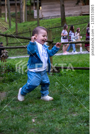 Toddler walking on grass in park near wooden fence Toddler walking on grass in park near wooden fence 138553865