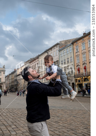 Father lifting toddler in european old town square Father lifting toddler in european old town square 138553964