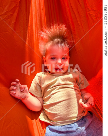 Smiling toddler on bright orange playground slide 138553985