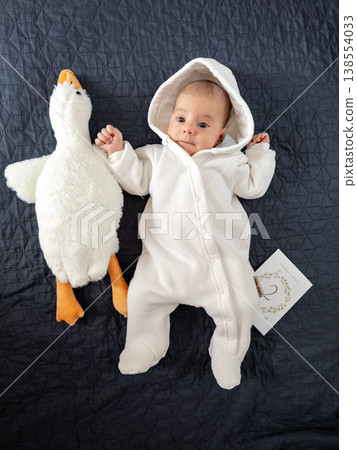 Newborn baby in white hooded onesie with plush goose toy Newborn baby in white hooded onesie with plush goose toy 138554033