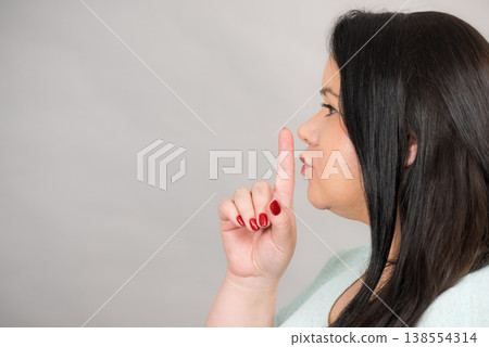 Woman asking for silence with finger on lips 138554314