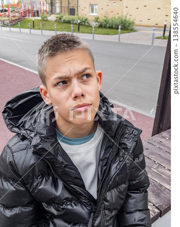 Teen wearing casual attire outdoors. Youthful individual with thoughtful expression on city street 138554640