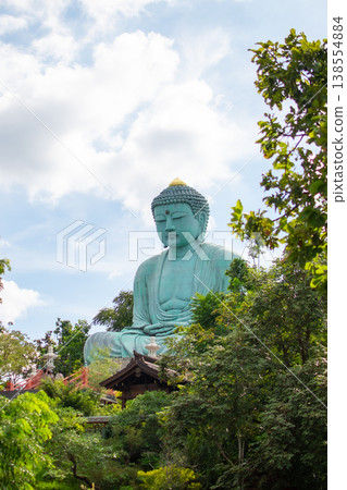 Large Great Buddha statue surrounded by green trees under cloudy sky Large Great Buddha statue surrounded by green trees under cloudy sky 138554884