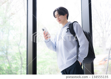 一位年輕男大學生在日常生活和通勤途中看著智慧型手機的場景。 一位年輕男大學生在日常生活和通勤途中看著智慧型手機的場景。 138555135