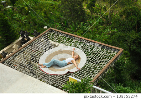Person relaxes on a net above green landscapes in Bali 138555274
