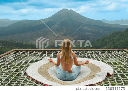 A person sits calmly and meditates while facing Mount Batur A person sits calmly and meditates while facing Mount Batur 138555275
