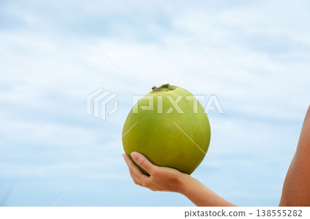 Person holds a green coconut at the beach in Bali Person holds a green coconut at the beach in Bali 138555282