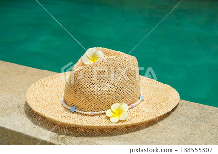 A straw hat with flowers rests on the edge of a pool in Bali A straw hat with flowers rests on the edge of a pool in Bali 138555302