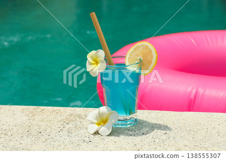 A colorful drink with flowers sits by the pool A colorful drink with flowers sits by the pool 138555307