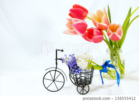 一輛迷你三輪車上擺放著一束風信子花,花瓶裡插著鬱金香。 一輛迷你三輪車上擺放著一束風信子花,花瓶裡插著鬱金香。 138555412