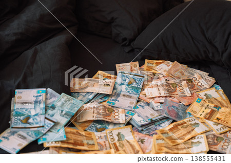 Pile of Kazakhstani tenge banknotes on black sofa, cash savings and wealth concept Pile of Kazakhstani tenge banknotes on black sofa, cash savings and wealth concept 138555431