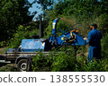 An operator loads tree branches into a wood chipper. 138555530