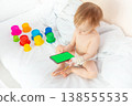 child in hospital lying in bed with mobile phone smiling 138555535