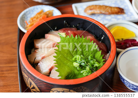 A seafood rice bowl served in a black lacquerware bowl, garnished with shiso leaves and chopped green onions for added color. A seafood rice bowl served in a black lacquerware bowl, garnished with shiso leaves and chopped green onions for added color. 138555537