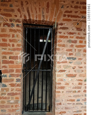 Andaman and Nicobar Islands , 29th May 2024 A weathered red brick wall and heavy iron-barred door of a solitary confinement cell at the historic Cellular Jail in Port Blair. 138555981