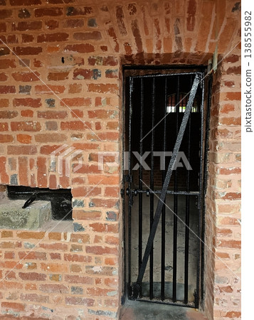 A close-up of a heavy iron-barred door and weathered brickwork of a solitary cell at the historic Cellular Jail in Port Blair. A close-up of a heavy iron-barred door and weathered brickwork of a solitary cell at the historic Cellular Jail in Port Blair. 138555982