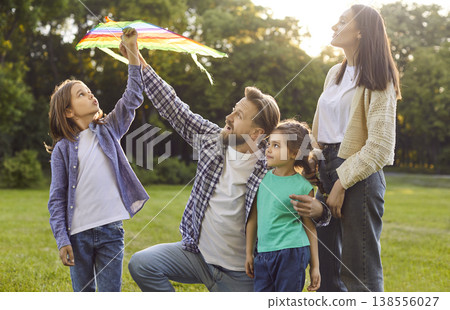 Happy family spending summer time holiday together outdoors in park, interacting with colorful kite 138556027
