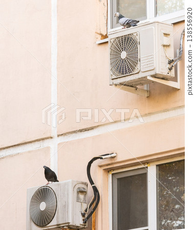 air conditioner is installed on facade of the building. air conditioner compressor is on wall. air conditioner is installed on facade of the building. air conditioner compressor is on wall. 138556920