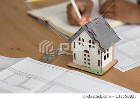 close up view of house layout that stands on table. female architect is working on creating. close up view of house layout that stands on table. female architect is working on creating. 138556923
