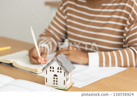 close up view of house layout that stands on table. female architect is working on creating. close up view of house layout that stands on table. female architect is working on creating. 138556924