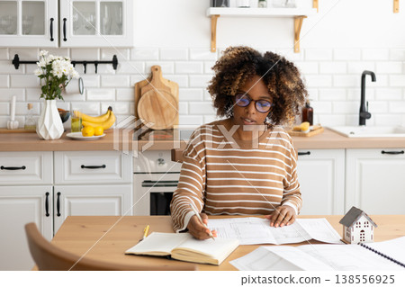 female architect designer is working, taking notes in notebook is mock up of house on table. female architect designer is working, taking notes in notebook is mock up of house on table. 138556925