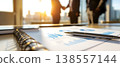 Photo of business meeting with financial charts and handshake in the background, city view, sunlight. 138557144