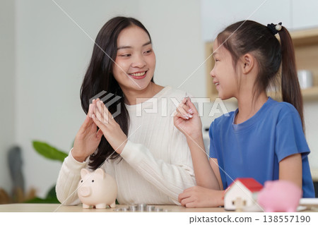 Mother teaching daughter financial literacy with piggy bank Mother teaching daughter financial literacy with piggy bank 138557190