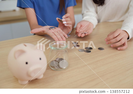Hands counting coins for savings with piggy bank Hands counting coins for savings with piggy bank 138557212